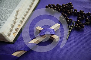 Holy cross with Bible and Rosary on purple cover background. Religious concept