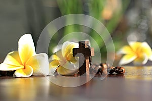 Holy Cross of rosary closeup in low angle view. Wooden rosary with Jesus Christ crucifix  and Bali frangipani flowers. Copy space. photo