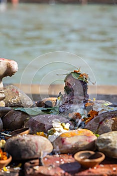 holy god shivalinga worshiped by devotee with flowers at river shore at morning