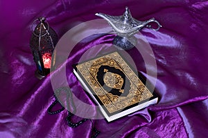 Holy islamic book Quran on Purple silk fabric with a rosary,Lantern and Egypt aladdin lamp - Ramadan kareem/Eid al fitr Concept.