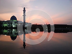 Holy Mosque in kajang view during calm sunrise with reflection at a lake (soft focus, shallow DOF, slight motion blur)