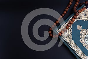 Holy Quran with arabic calligraphies translation meaning of Al-Quran and Rosary or Tasbih on black background photo