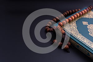 Holy Quran with arabic calligraphies translation meaning of Al-Quran and Rosary or Tasbih on black background photo