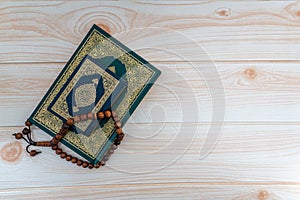 Holy Quran with arabic calligraphies translation meaning of Al-Quran and Rosary or Tasbih on wooden background photo