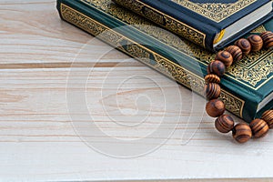 Holy Quran with arabic calligraphies translation meaning of Al-Quran and Rosary or Tasbih on wooden background photo