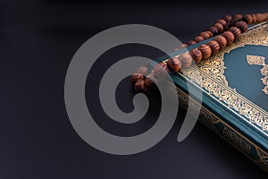 Holy Quran with arabic calligraphies translation meaning of Al-Quran and Rosary or Tasbih on black background photo