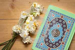 Holy Quran book and daffodils on the wooden background. Ramadan