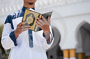 Holy Quran in Hand. Muslim man holding Quran