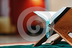 Holy Quran with prayer rosary beads on wooden stand