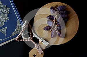 holy quran with dates fruits and tasbih beads isolated at dakr background, suitable for ramadhan kareem. photo