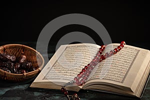 The holy Quran and Tasbih rosary beads on dark background