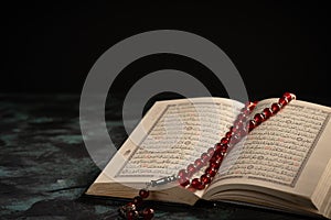The holy Quran and Tasbih rosary beads on dark background