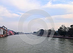 The Holy River Ganges - Ganga with both Banks, Buildings and White Clouds in Blue Sky - Haridwar, Uttarakhand, India