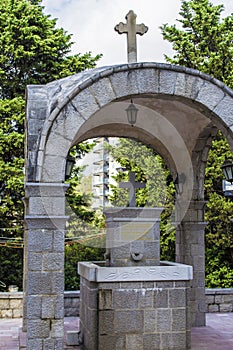 A holy spring of water surrounded by a stone with a cross and a stone awning. Montenegro. Becici