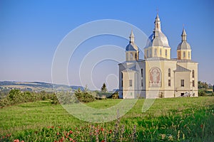 Holy temple on a hill with poppies against a clear sky. photo