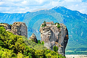 Holy Trinity Monastery on a top of the rock on the mountain range background