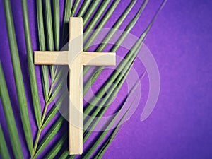 Holy Week, Lent, Palm Sunday, Good Friday, Easter Sunday Concept. Wooden cross with palm leaf in purple background.