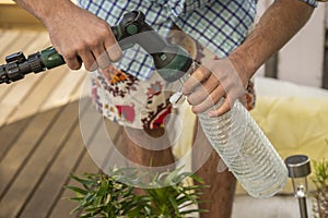 Man wearing a plaid shirt filling a water bottle to water plants photo