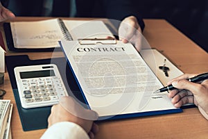 Home agents talking to home buyers who are signing contracts at the office