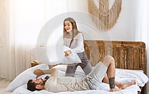 Home alone concept. Happy couple fights pillows, girl defeats guy
