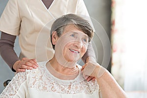 Assistant supporting smiling old lady