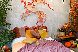 Home autumn decor. Cozy fall bedroom interior bed with orange pillows, flowers, pumpkins, Autumn decoration