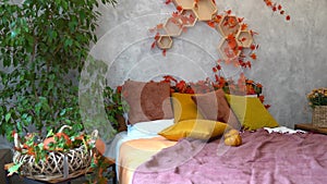 Home autumn decor. Cozy fall bedroom interior bed with orange pillows, flowers, pumpkins, Autumn decoration