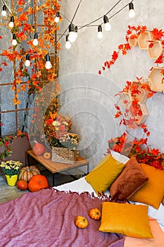 Home autumn decor. Cozy fall bedroom interior bed with orange pillows, flowers, pumpkins, Autumn decoration