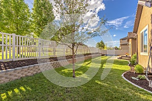 Home backyard with vibrant lawn and raised planting bed along white picket fence