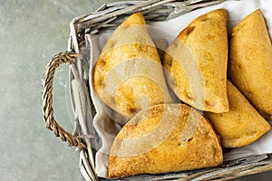 Home Baked Empanadas Turnover Pies with Pisto Vegetable Cheese Filling in Tomato Sauce in Wicker Basket. Spanish Pastry Dark Table