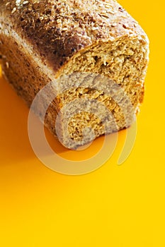 Home baked fresh loaf of bead from spelt whole grain rye flour with seeds bran on bright yellow background. Breakfast healthy diet