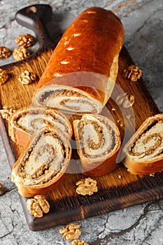 Home baked nut roll, bejgli, traditional sweet bread stuffed with walnut filling closeup on the wooden board. Vertical
