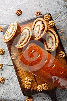 Home baked nut roll, bejgli, traditional sweet bread stuffed with walnut filling closeup on the wooden board. Vertical top view