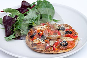 Home baked vegan mini pizza with ruccola salad