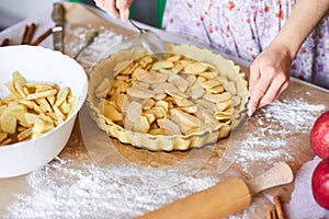 Home baking of holidays classic sweet pies. Woman hands fixing pastry dough in a tray and pumpkin pie ingredients. Preparing