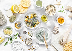 Home beauty products - clay, oatmeal, coconut oil, turmeric, lemon, scrub, dry flowers and herbs, sponges, soap, facial brush on l