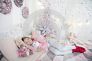 Home is the best place in the world. Girl little kid relaxing on bed light interior with christmas decorations