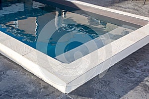 Home blue swimming pool with stone coping with a waxed concrete terrace house