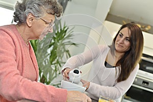 Home carer serving a tea to a senior lady