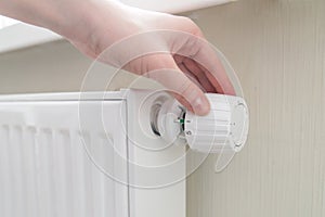 Home central heating system. Woman`s hand turns the regulator