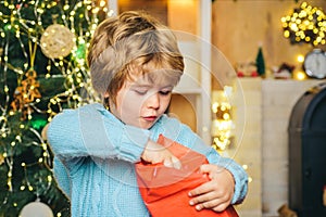 Home Christmas atmosphere. Cheerful cute child opening a Christmas present. Happy child with Christmas gift. Happy kid