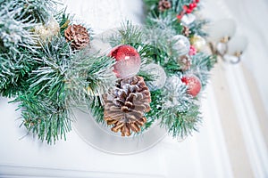 Home Christmas decoration on white wall , fir branches, garland and pinecone, angel figure, christmas card with copy