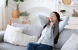 Home Comfort. Young Asian Lady Relaxing On Cozy Sofa In Living Room