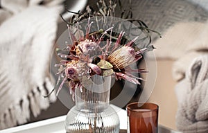 Home composition with a bouquet of protea flowers and candles.