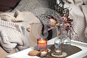 Home composition with a bouquet of protea flowers and candles.