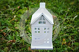 Home concept. White house model on green grass. Insurance of house. New home.