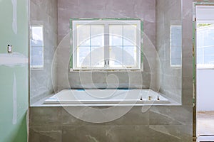 Home construction bathtub tiled walls after installing remodeling master bathroom patching drywall