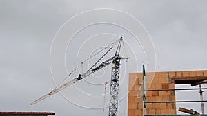 Home construction. Construction crane and scaffolding on cloudy gray sky background