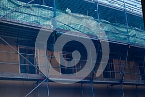 Home construction.Construction and repair of the house.Scaffolding in a protective blue grid.