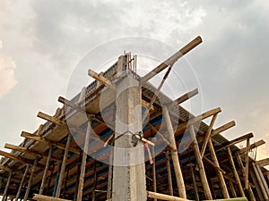 Home construction with wooden scaffolding from bottom view under cloudy sky